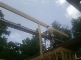 Carpenter setting a ridge beam over a new addition frame — Ice Dam Removal by Roofing Brothers in Adolphus
