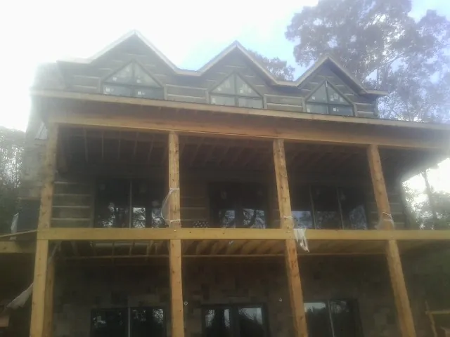 Dormers and porch framing on a large log home under construction — Roof Coating work by our crew in Adolphus