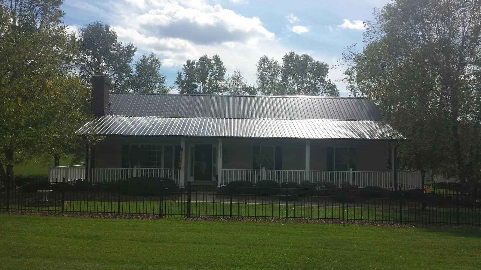 Gray metal roof on a brick ranch with a full width front porch — Gutter Guard Installation work by our crew in Adolphus