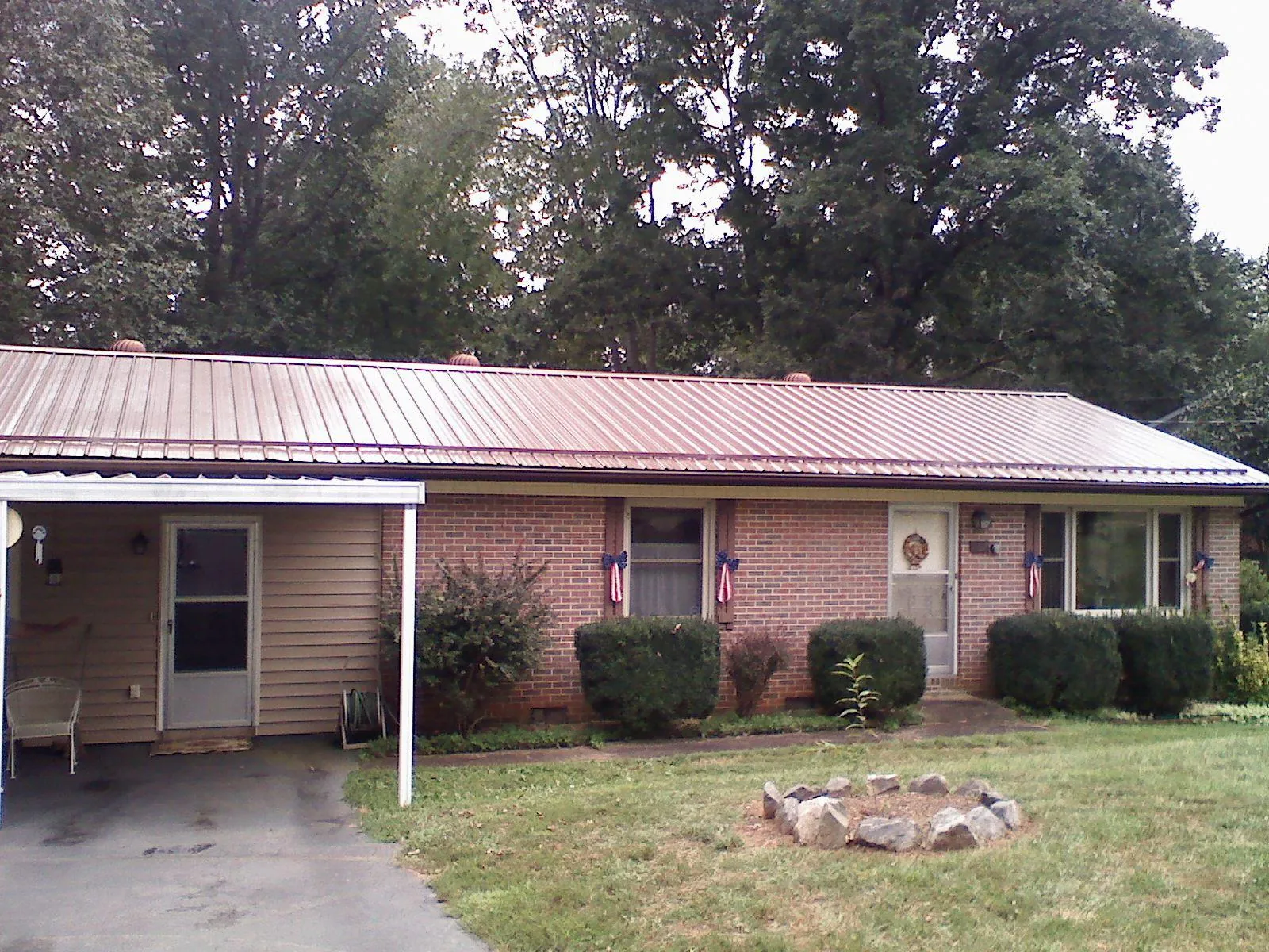 Bronze metal roof and carport on a brick ranch home — Roof Repair work by our crew in Adolphus