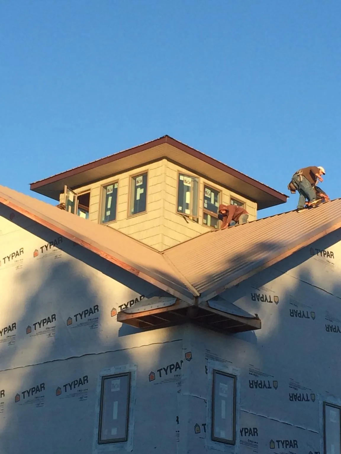 Roofers working around a rooftop cupola on a new metal roof at sunset — Roof Waterproofing in Adolphus by Roofing Brothers